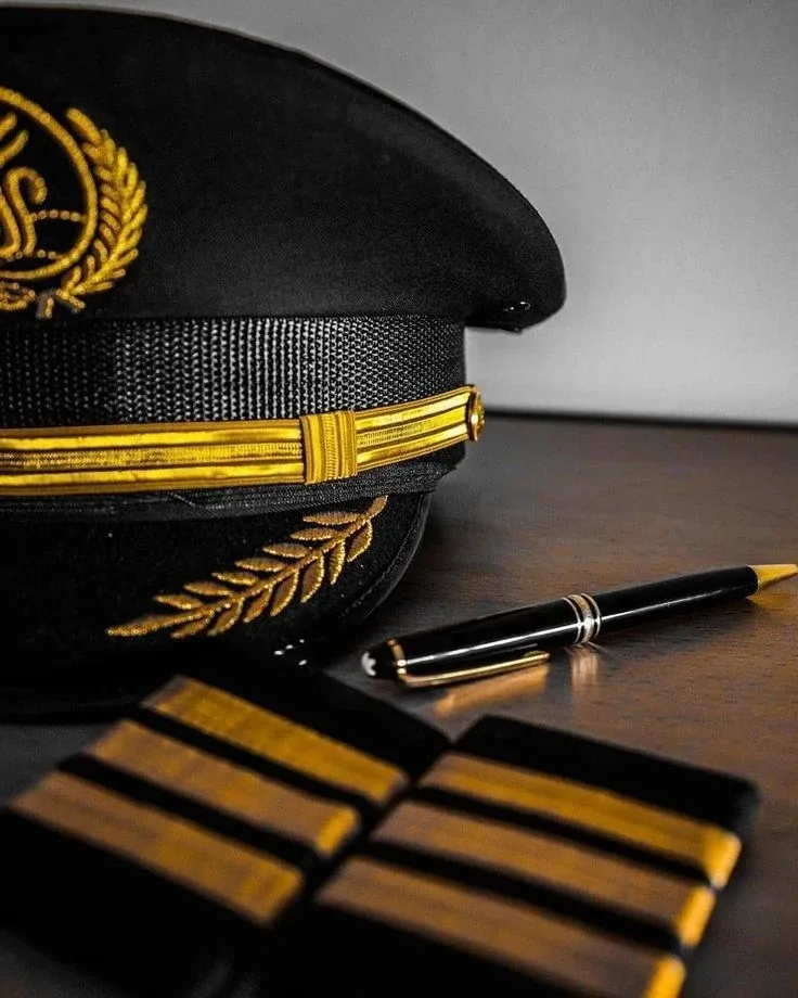 Pilot cap, pen and four-stripe epaulettes on a desk