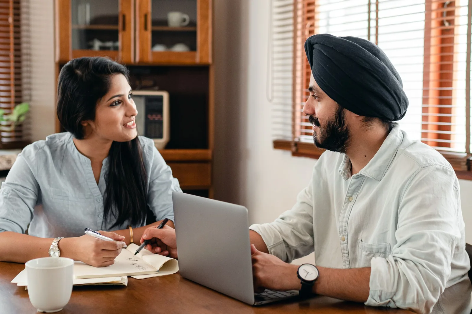 Two colleagues talking at a desk with a laptop