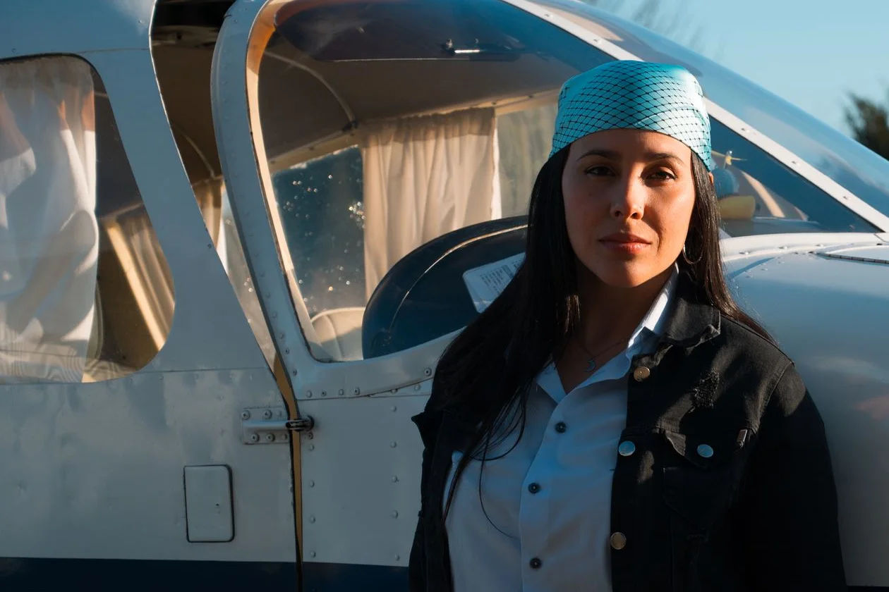 Young woman standing beside a small propeller aircraft