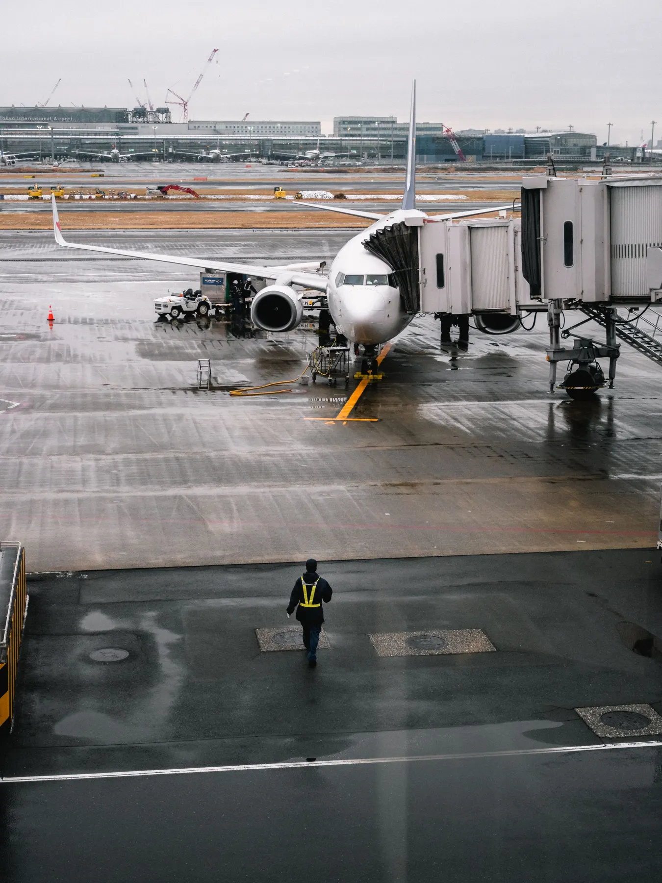 Person walking across a wet apron towards a parked airliner