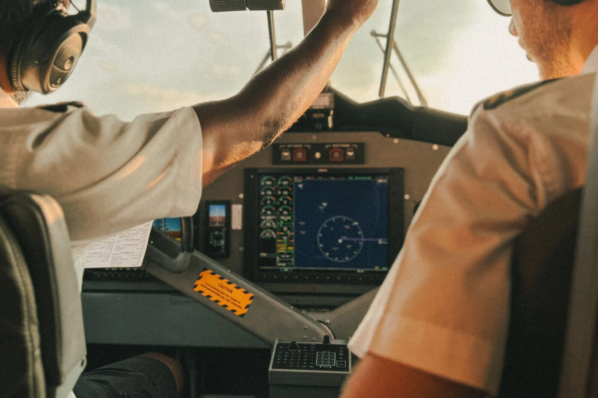 Two pilots at the controls of a turboprop cockpit at golden hour