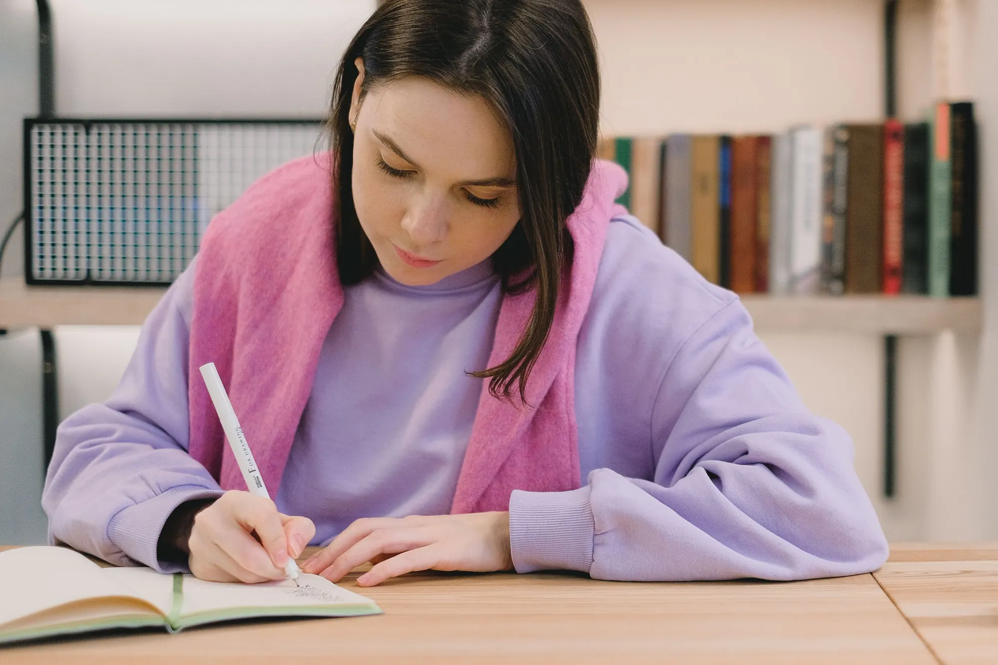 Young woman writing notes at a library desk