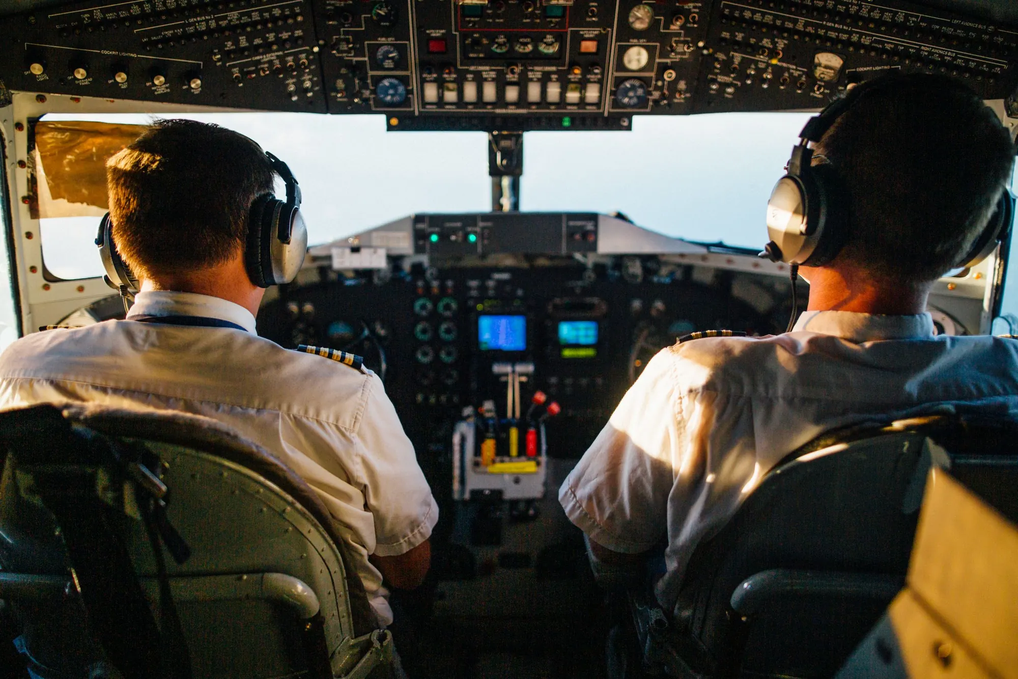 Two pilots in headsets at an airliner flight deck