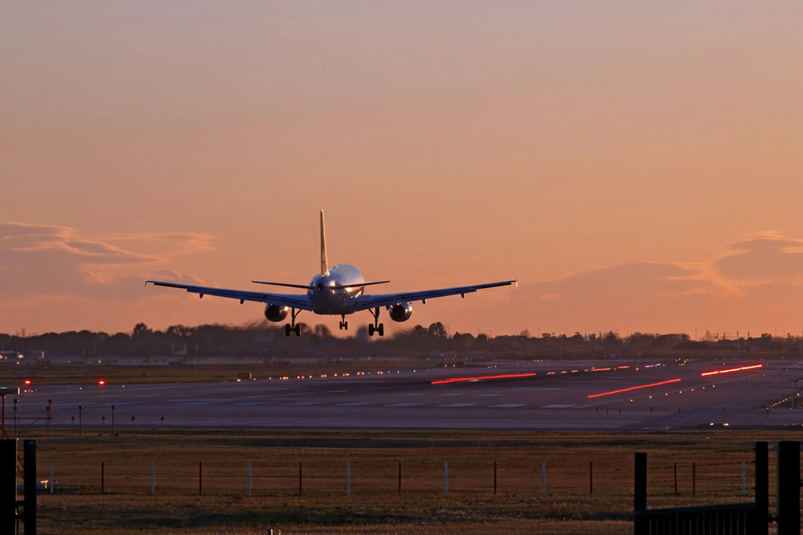 Airliner on final approach to a lit runway at dusk