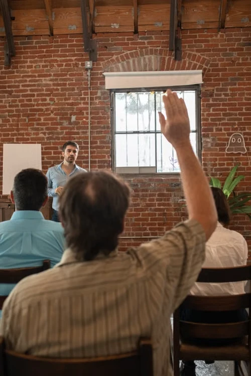 A speaker taking questions from a raised hand at a counselling session