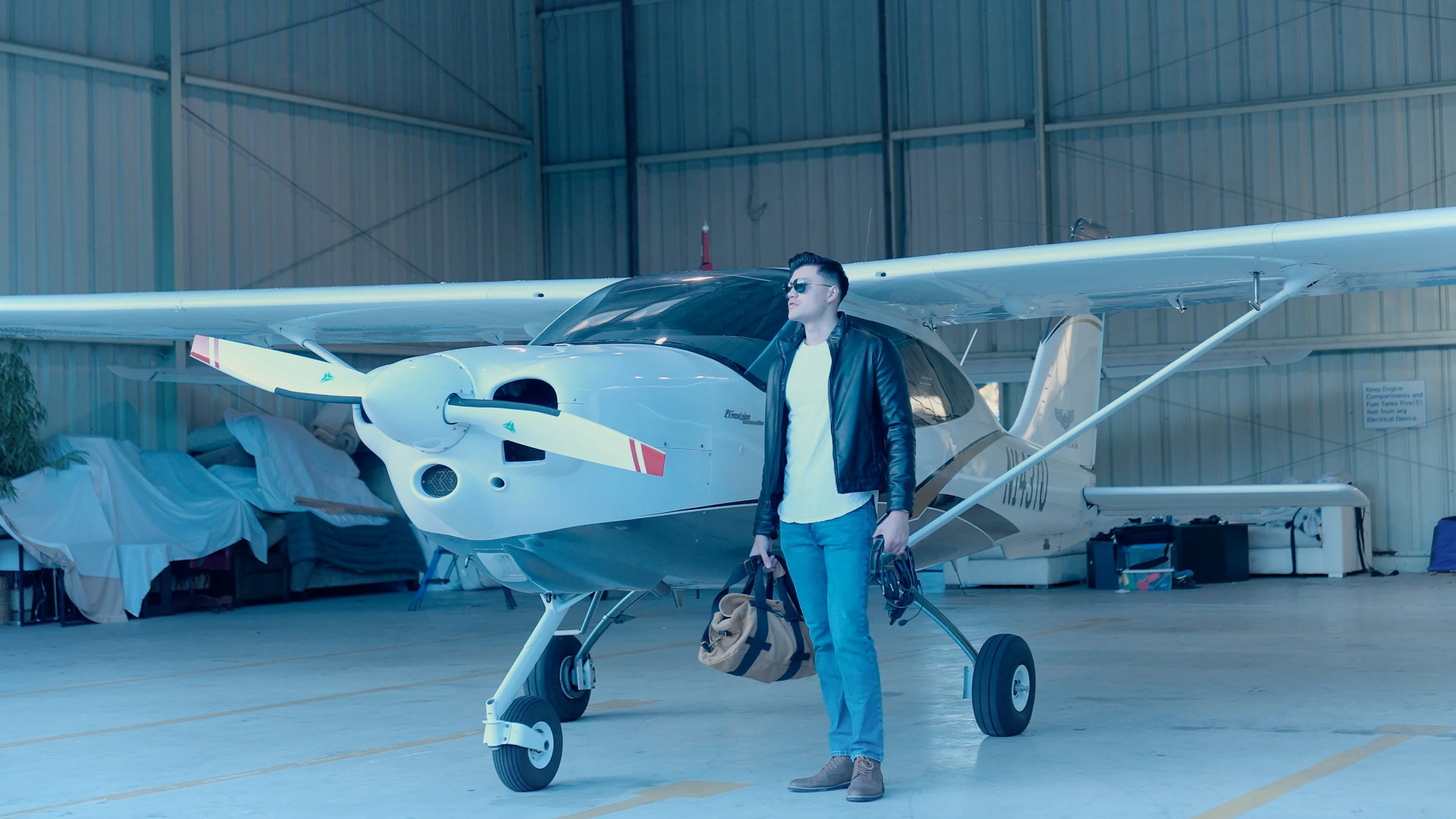 Person standing beside a light aircraft in a hangar