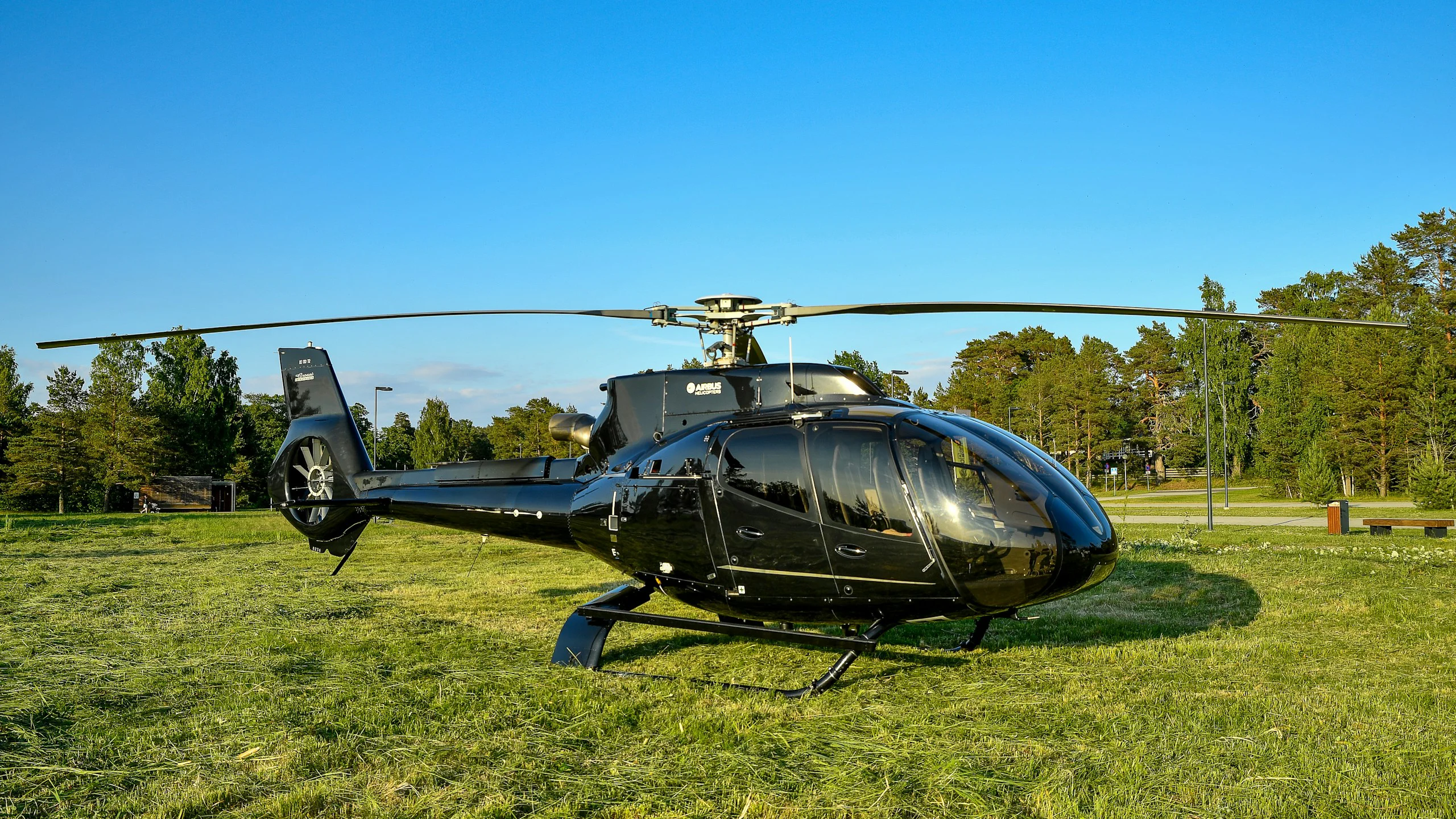 Black helicopter parked on a grass airfield